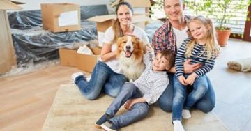 Glückliche Familie mit zwei Kindern und Hund im neuen Haus nach Umzug